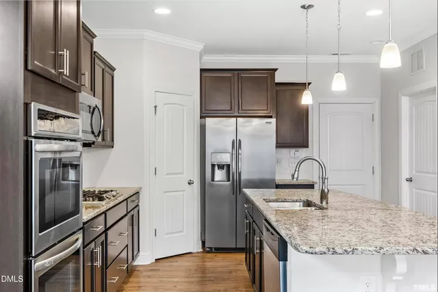 a kitchen with kitchen island a counter space a sink appliances and cabinets