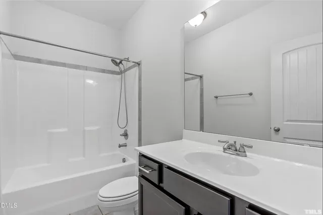 a view of a livingroom with a fireplace a ceiling fan and windows