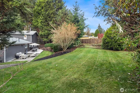 a view of a backyard with table and chairs and potted plants and large trees