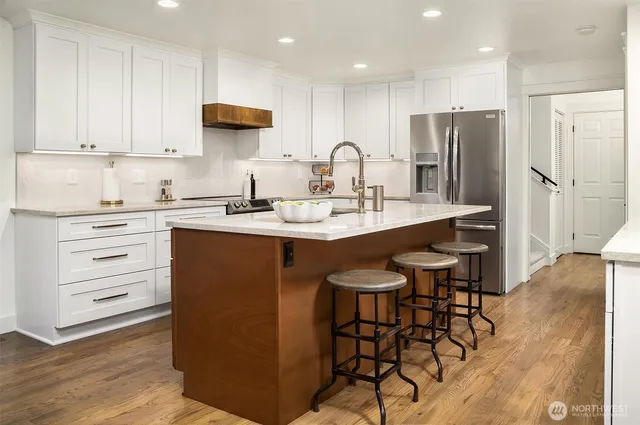 a kitchen with stainless steel appliances granite countertop a table chairs refrigerator and sink