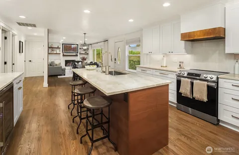 a kitchen with stainless steel appliances granite countertop a table chairs stove a sink dishwasher and cabinets with wooden floor