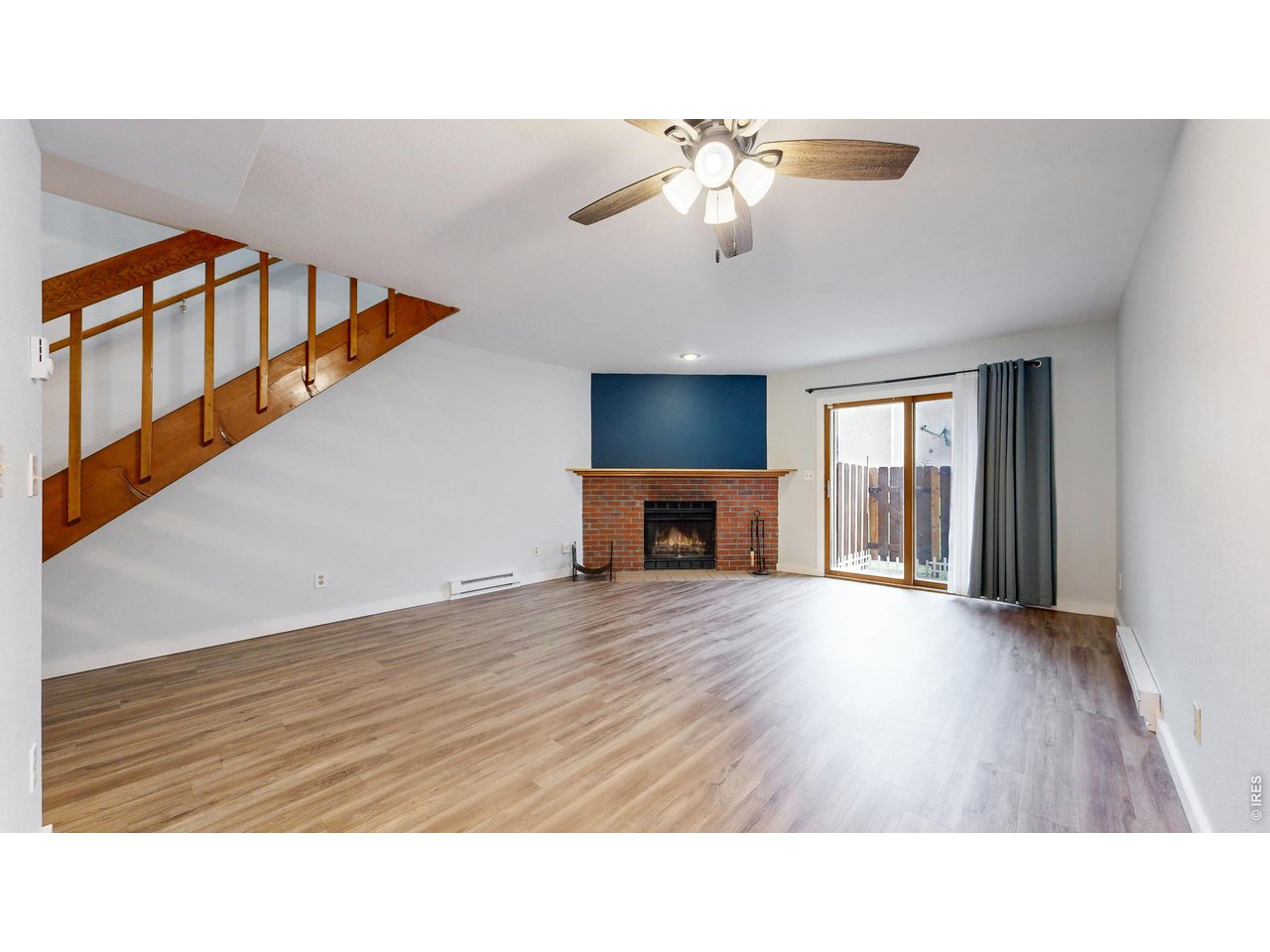 1440 Edora Road, Unit 19 Fort Collins, CO 80525 - Photo 4 of 30 Bright living room with new flooring and a cozy brick fireplace, plus sliding doors out to the patio