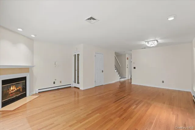a view of an empty room with wooden floor and a fireplace