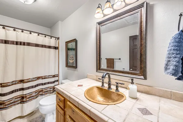 a bathroom with a granite countertop sink a mirror a toilet and a shower curtain
