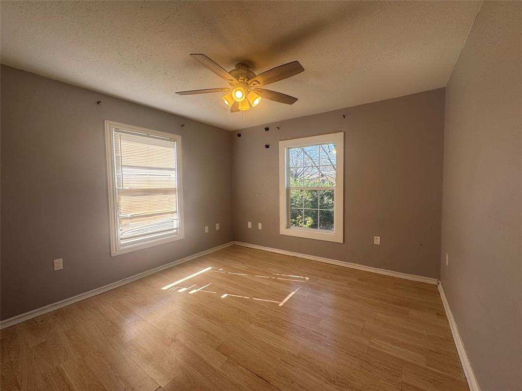 3520 Colcord Avenue Waco, TX 76707 - Photo 12 of 17 Unfurnished room with a textured ceiling, light wood-type flooring, and a ceiling fan