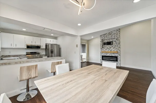 a kitchen with stainless steel appliances kitchen island granite countertop a refrigerator oven a sink dishwasher and white cabinets with wooden floor