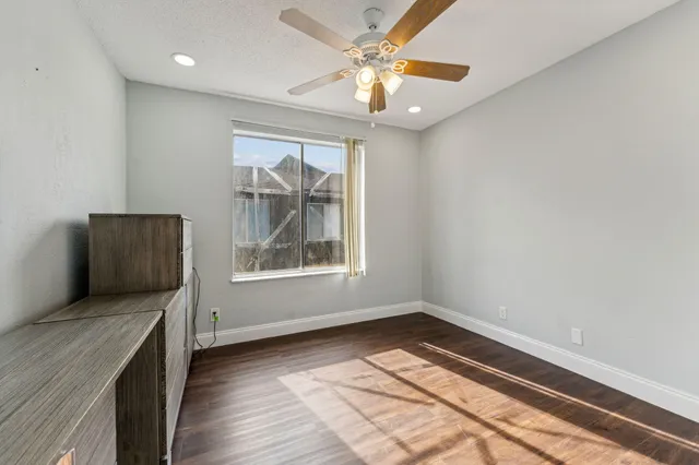 an empty room with wooden floor cabinet and windows