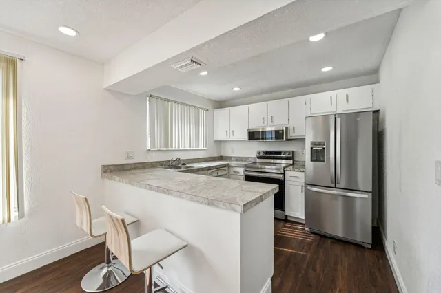 a kitchen with granite countertop a refrigerator stove microwave and wooden floor