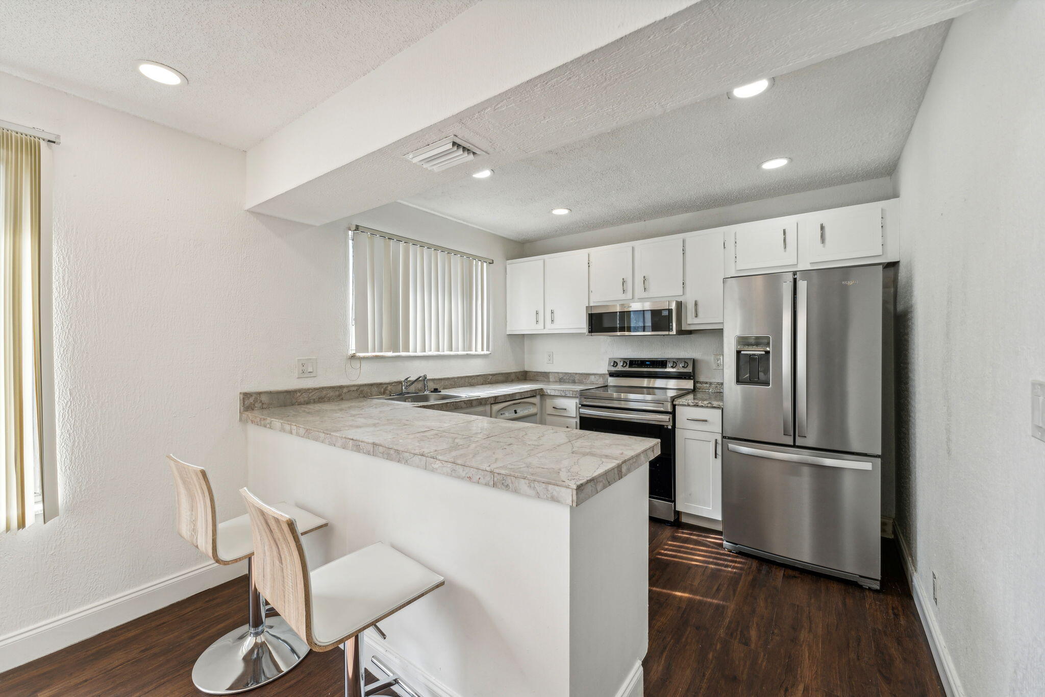 5312 Bosque Lane, Unit 80 West Palm Beach, FL 33415 - Photo 3 of 20 a kitchen with granite countertop a refrigerator stove microwave and wooden floor