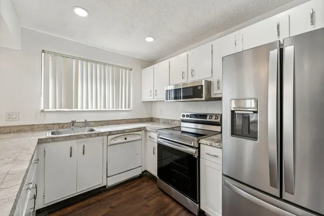 a kitchen with cabinets stainless steel appliances a sink and a window