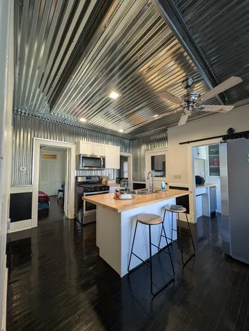 a living room with stainless steel appliances kitchen island granite countertop furniture and a wooden floor