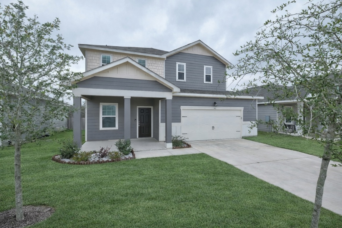 View of front of house with covered porch, a front yard, concrete driveway, and an attached garage