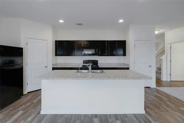 a view of living room with stainless steel appliances kitchen island a flat screen tv and a refrigerator