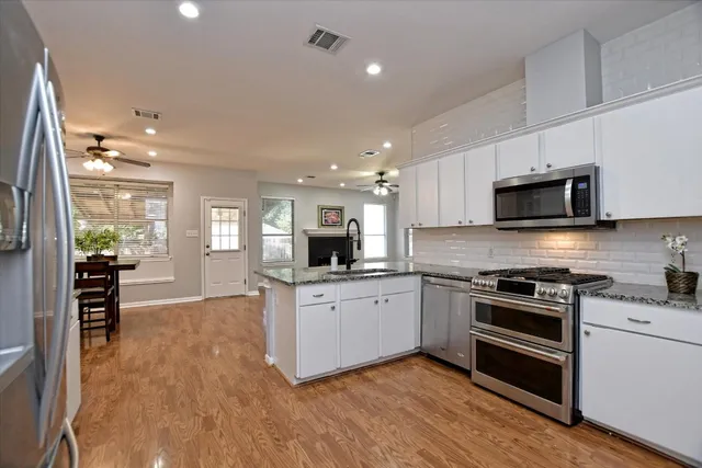 a kitchen with stainless steel appliances kitchen island granite countertop a stove top oven a sink a dining table and chairs