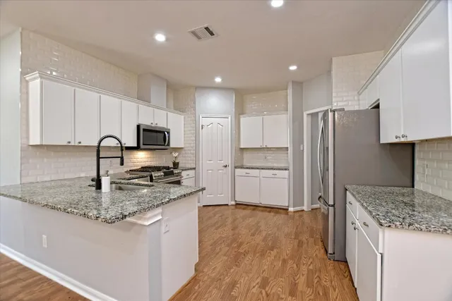 a kitchen with stainless steel appliances granite countertop a sink stove and refrigerator