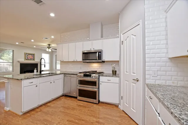 a kitchen with granite countertop a sink stainless steel appliances and white cabinets