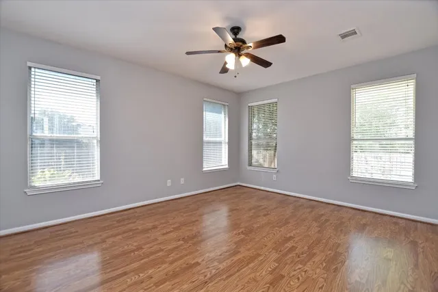 a view of an empty room with a window and wooden floor