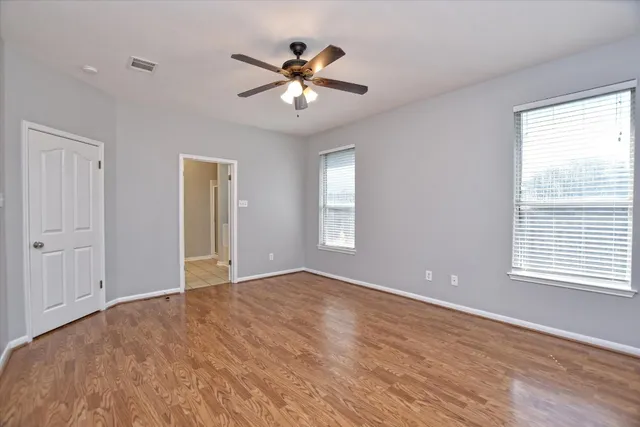 a view of an empty room with chandelier fan and a window