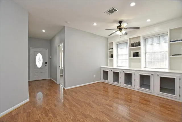 a view of an empty room with window and wooden floor