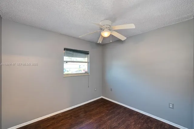 a view of room with hardwood floor and a ceiling fan