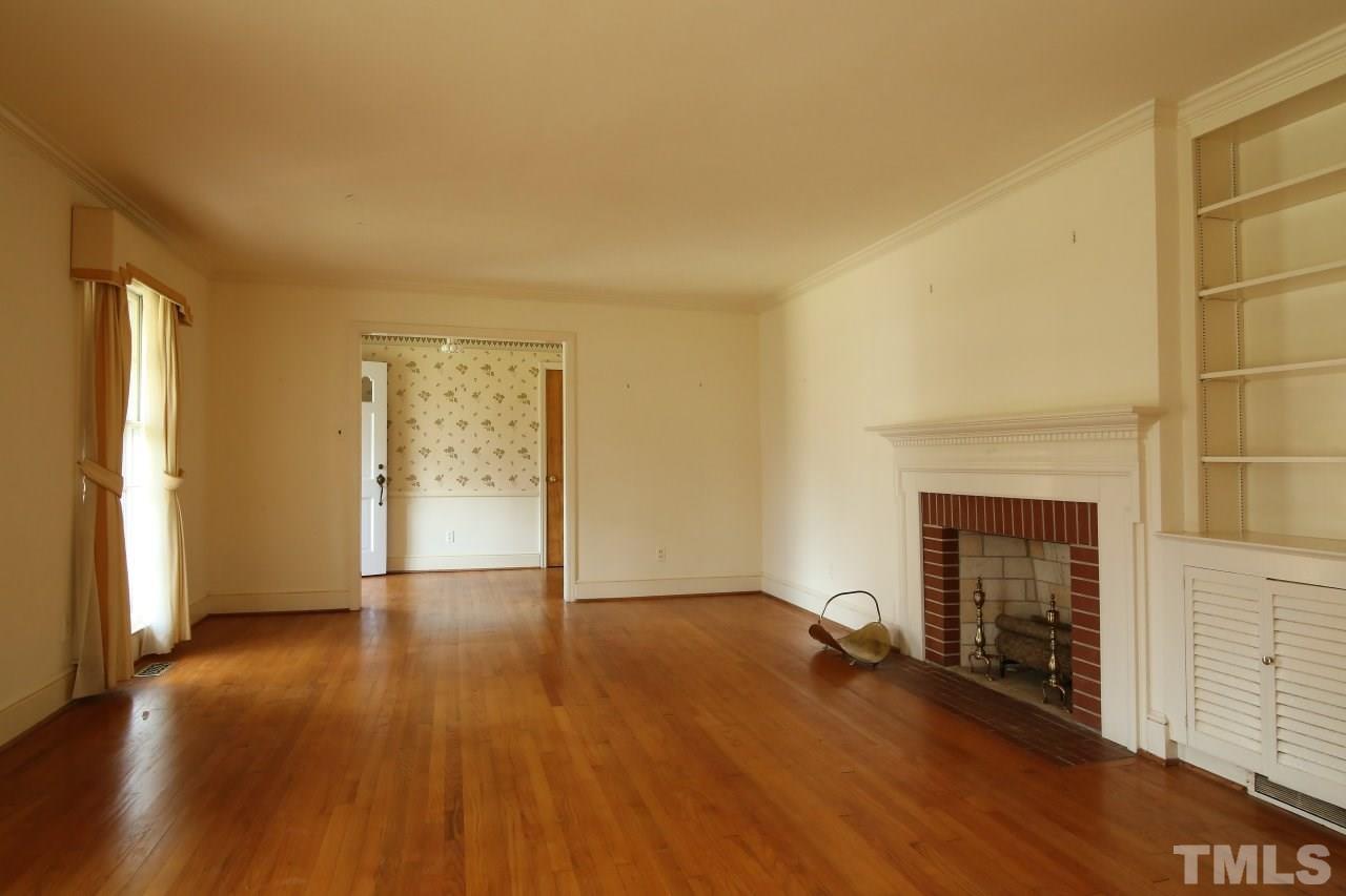 516 Chesterfield Road Raleigh, NC 27608 - Photo 5 of 21 an empty room with wooden floor fireplace and windows