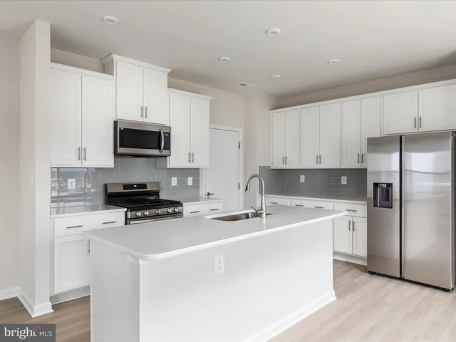 a kitchen with stainless steel appliances a stove a sink a refrigerator a microwave and cabinets