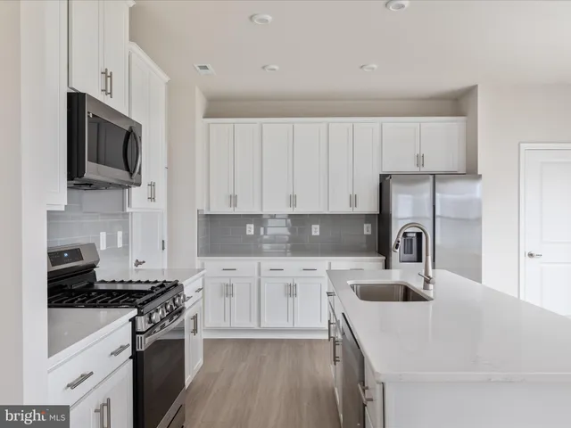 a kitchen with stainless steel appliances granite countertop a sink stove microwave and refrigerator