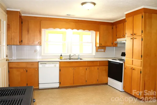 a kitchen with stainless steel appliances granite countertop a refrigerator a sink dishwasher and white cabinets with wooden floor