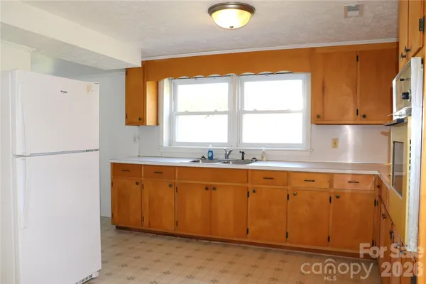 a kitchen with stainless steel appliances granite countertop a stove a sink and white cabinets with wooden floor