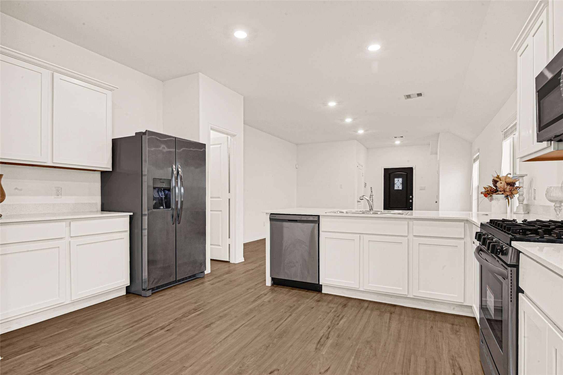 2010 Ballesteros Street Crosby, TX 77532 - Photo 8 of 24 a kitchen with a refrigerator a stove top oven a sink and white cabinets with wooden floor