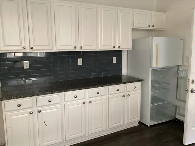 a kitchen with granite countertop white cabinets and sink