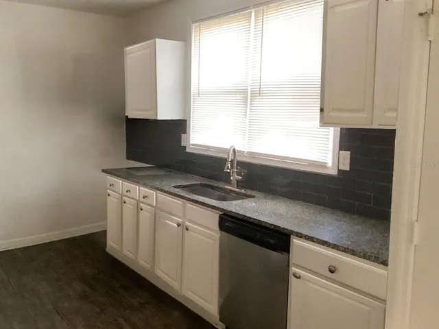a kitchen with granite countertop white cabinets and a sink
