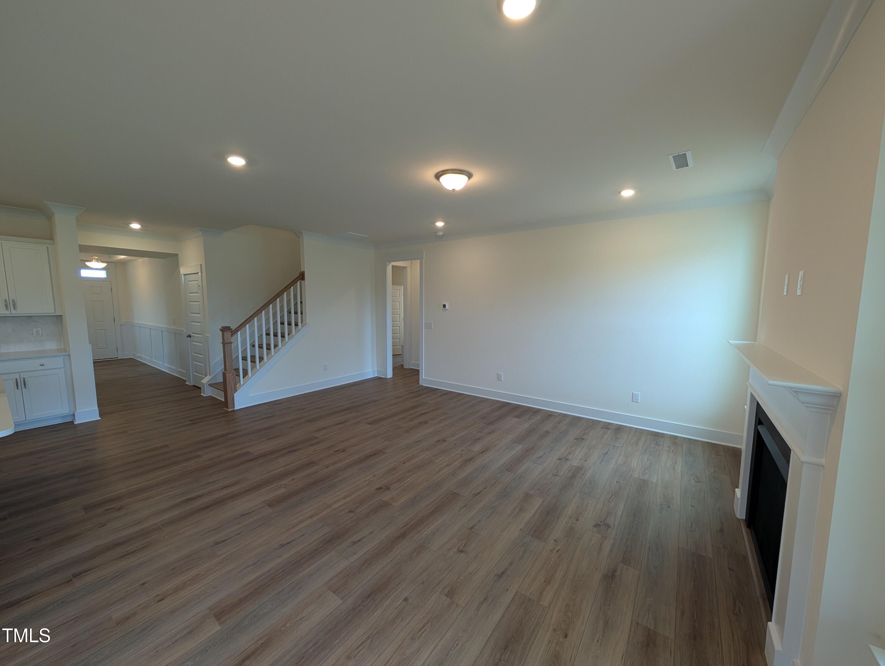 266 Weddington Way Benson, NC 27504 - Photo 8 of 35 a view of an empty room with wooden floor and a kitchen