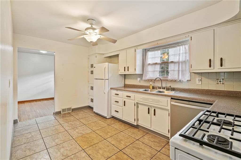124 Clover Drive Monaca, PA 15061 - Photo 7 of 27 a kitchen with white cabinets a stove a sink and a window