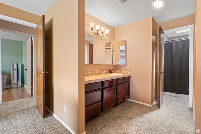 165 Pheasantbrook Drive Centerville, UT 84014 - Photo 20 of 30 Master bedroom leading into bathroom with light carpet, vanity, curtained shower, and a textured ceiling
