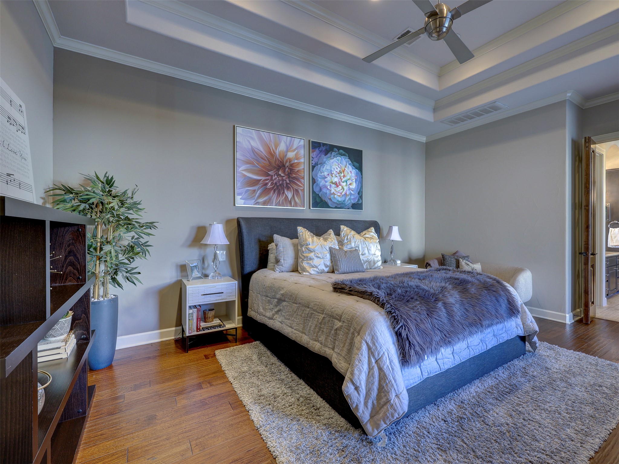 11805 Pleasant Panorama View Austin, TX 78738 - Photo 19 of 40 Retreat to a sanctuary of absolute luxury. This sprawling primary bedroom features rich hardwood flooring and a tray ceiling. The expansive layout accommodates a seating area and soft neutral tones create a serene atmosphere.