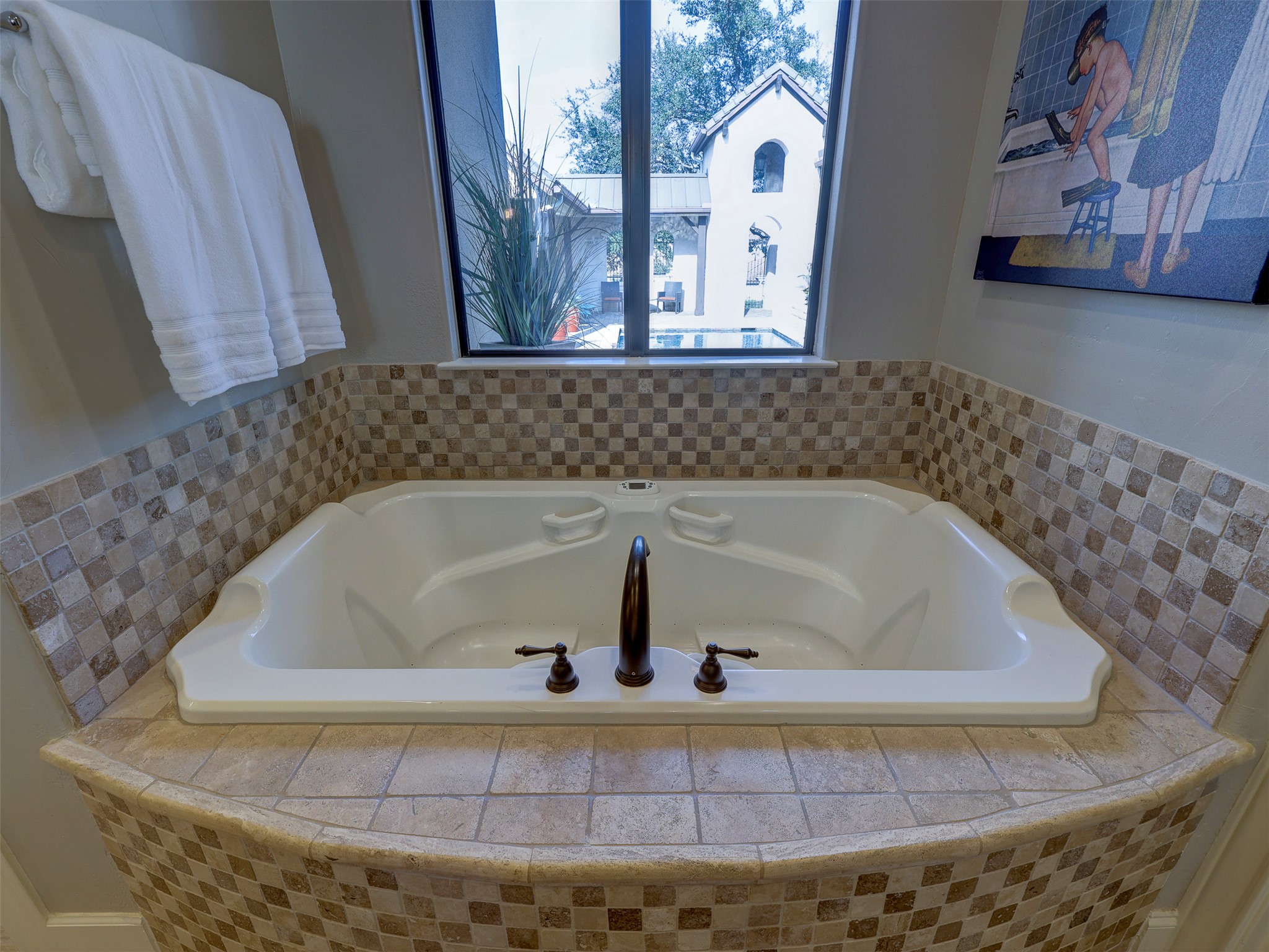 11805 Pleasant Panorama View Austin, TX 78738 - Photo 22 of 40 Indulge in a spa like experience within your own home. This oversized soaking tub is framed by intricate mosaic tile work and strategically positioned beneath a large picture window, offering tranquil views of the private courtyard and pool area.