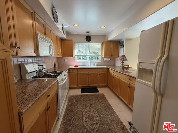 a kitchen with stainless steel appliances granite countertop a refrigerator a sink dishwasher a stove top oven a refrigerator and cabinets