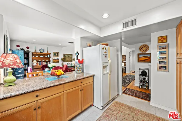 a kitchen with granite countertop a refrigerator and a lot of stuff