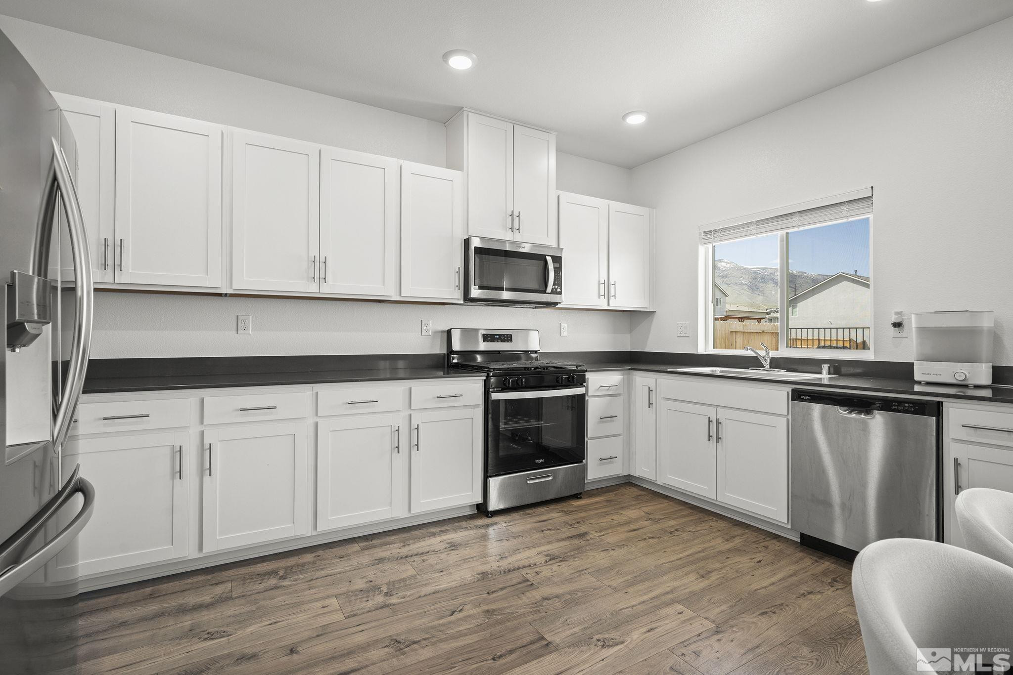 583 Iris Rainbow Drive Reno, NV 89506 - Photo 9 of 22 a kitchen with granite countertop a stove top oven sink and cabinets