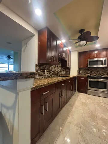 a kitchen with stainless steel appliances granite countertop a refrigerator and a stove
