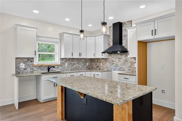 a kitchen with stainless steel appliances granite countertop a sink a stove a refrigerator and island with wooden floor