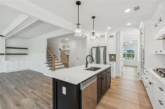 a kitchen with stainless steel appliances a sink a stove a refrigerator and cabinets