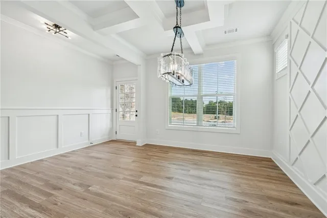 an empty room with wooden floor cabinet and windows