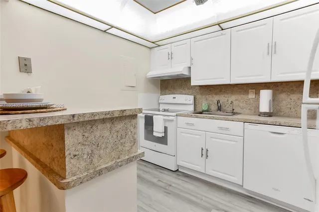 a kitchen with white cabinets and white appliances