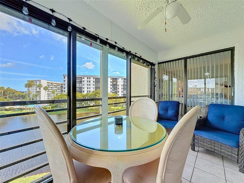 2309 South Cypress Bend Drive, Unit 515 Pompano Beach, FL 33069 - Photo 13 of 14 a view of a dining room with furniture a chandelier and large windows