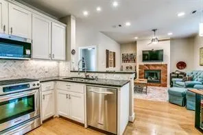 a kitchen with kitchen island granite countertop a stove a sink and a white cabinets