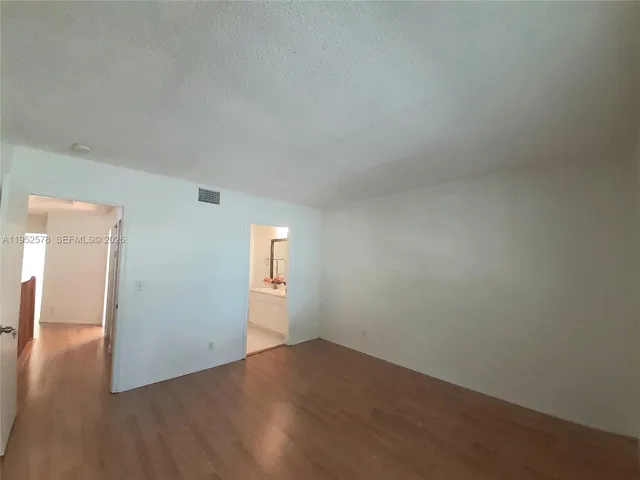 an empty room with wooden floor & windows