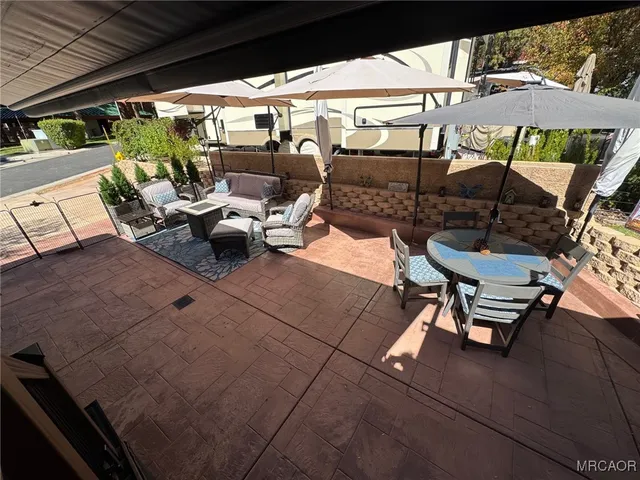a view of a patio with table and chairs under an umbrella with a barbeque