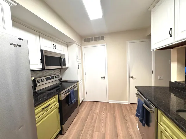 a kitchen with stainless steel appliances a stove a microwave and a hard wood floor